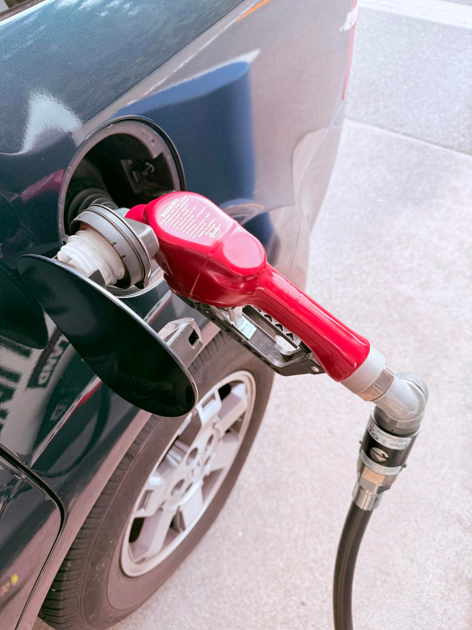 Close-up of a red gas pump fueling a car at a gas station, depicting the refueling process.